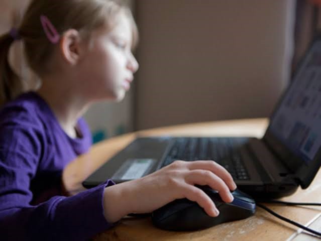 طفلة تجلس أمام شاشة لابتوب طفلة تجلس أمام شاشة لابتوب